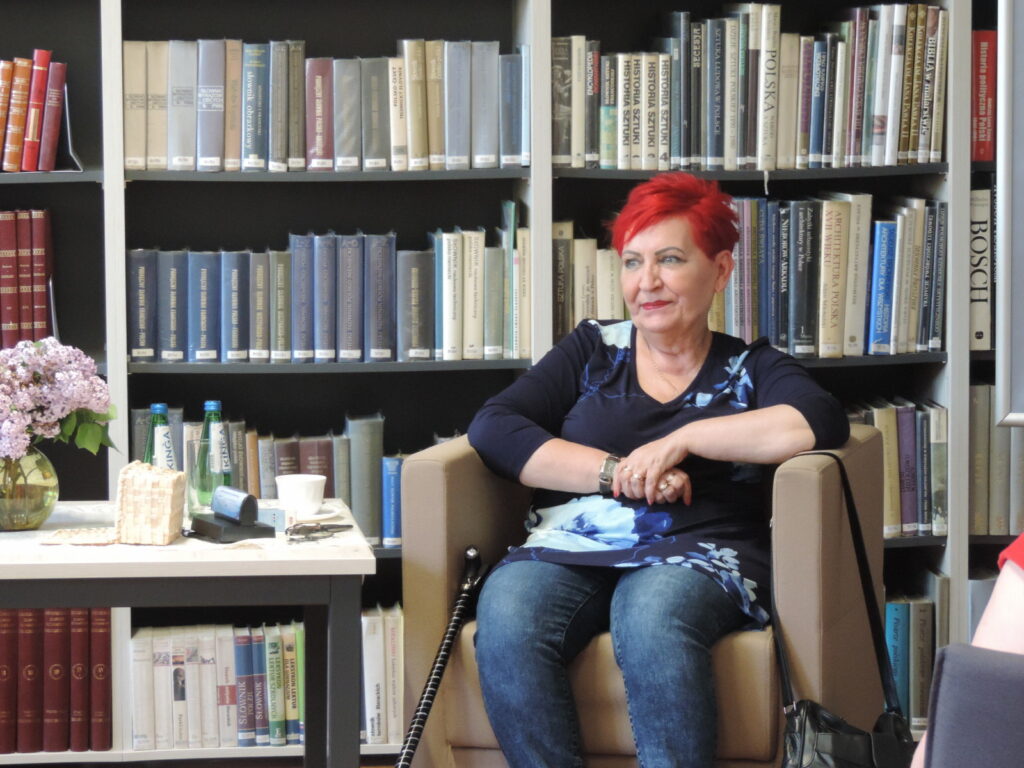 Pisarka Hanna Greń na tle regału z książkami